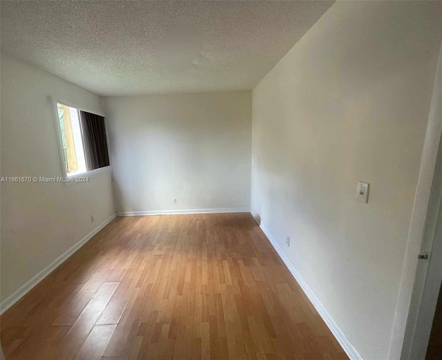 spare room with a textured ceiling and light hardwood / wood-style flooring