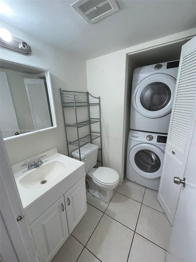 bathroom with toilet, stacked washer and clothes dryer, vanity, and tile patterned floors