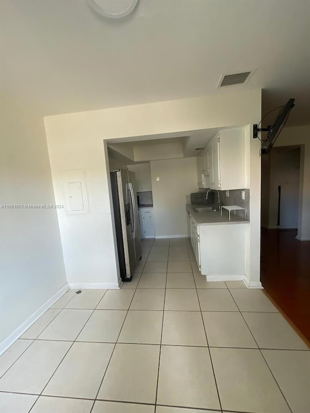 kitchen featuring light tile patterned floors, sink, tasteful backsplash, white cabinetry, and stainless steel fridge