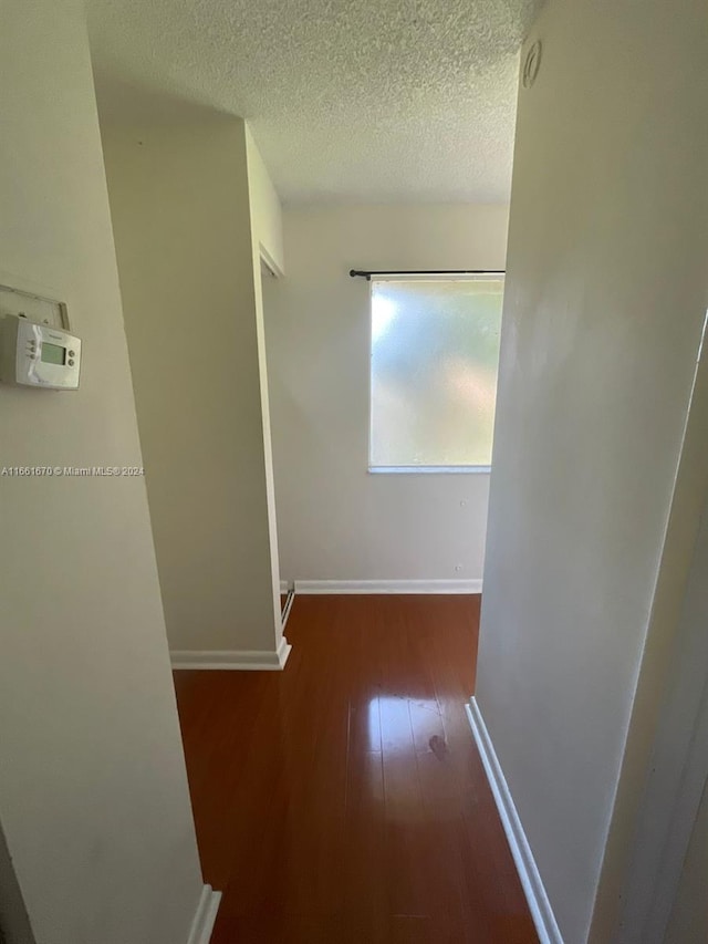 hallway featuring dark wood-type flooring and a textured ceiling