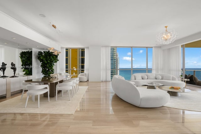 living room with a water view, a wall of windows, a chandelier, and a healthy amount of sunlight