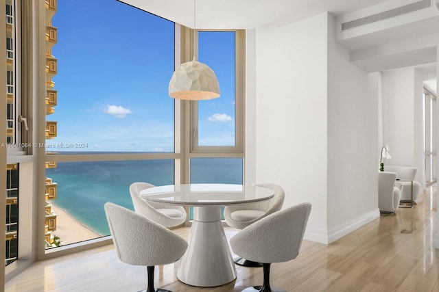 dining room with a water view, hardwood / wood-style flooring, and plenty of natural light