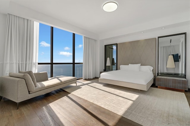 bedroom featuring a water view and hardwood / wood-style flooring