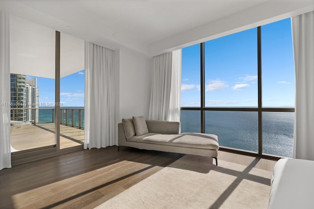 sitting room with expansive windows, hardwood / wood-style flooring, plenty of natural light, and a water view