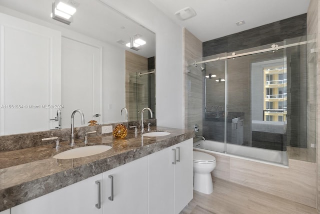 full bathroom with combined bath / shower with glass door, vanity, and toilet