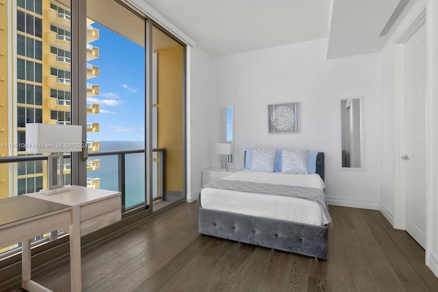 bedroom featuring a wall of windows, a water view, and dark hardwood / wood-style floors