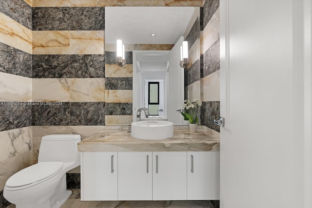 bathroom featuring tile walls, vanity, and toilet