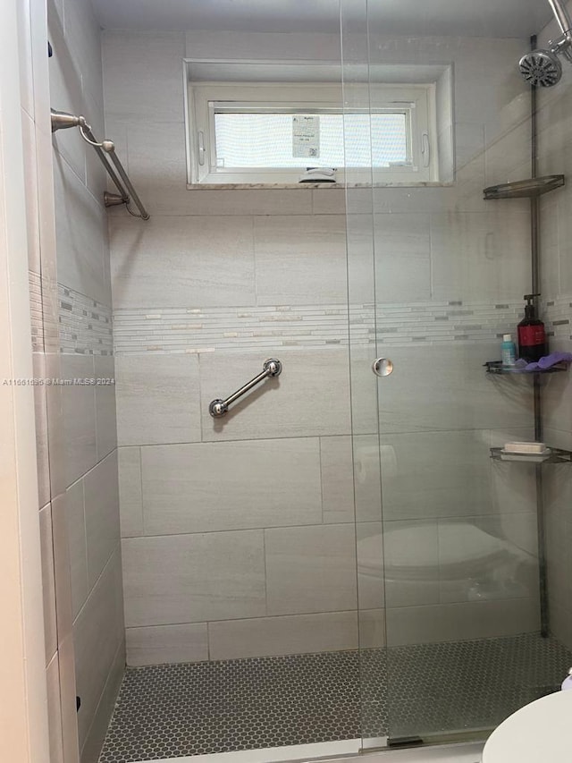 bathroom featuring a shower with shower door and toilet