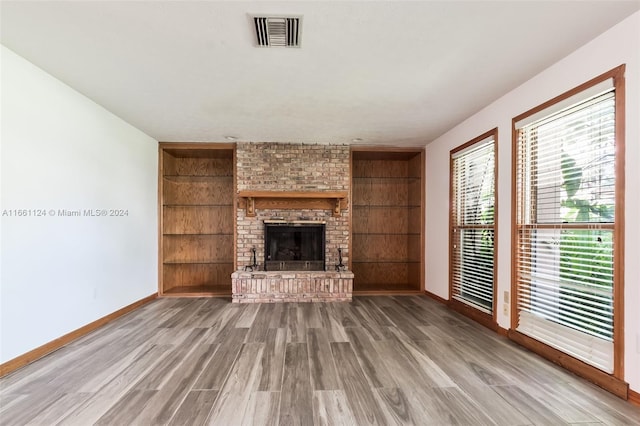 unfurnished living room featuring hardwood / wood-style flooring, a fireplace, and built in features