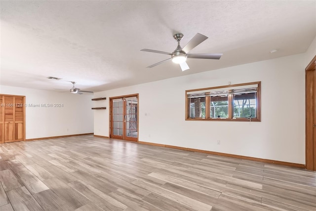 empty room featuring a textured ceiling, light hardwood / wood-style floors, and ceiling fan