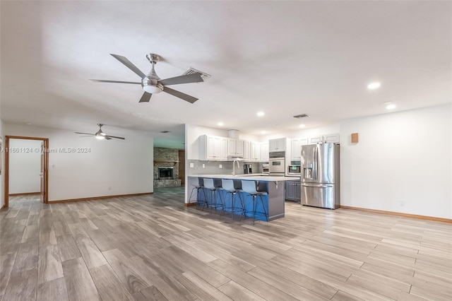 kitchen featuring light wood-type flooring, white cabinets, a kitchen breakfast bar, appliances with stainless steel finishes, and ceiling fan