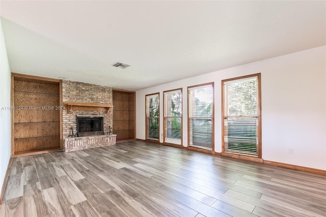 unfurnished living room with a fireplace, built in features, and hardwood / wood-style floors