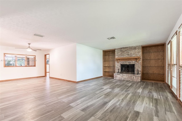 unfurnished living room with light hardwood / wood-style floors, ceiling fan, plenty of natural light, and a fireplace