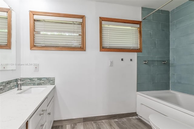 full bathroom featuring hardwood / wood-style floors, vanity, toilet, and tiled shower / bath