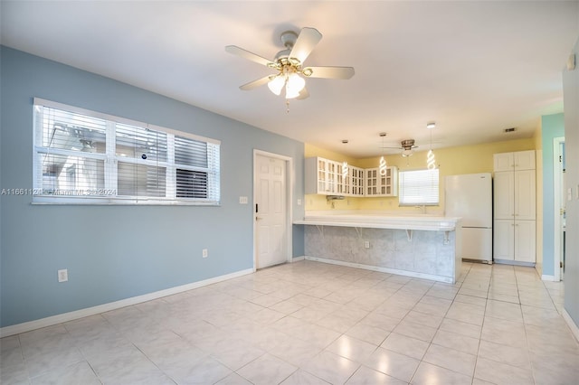 kitchen with pendant lighting, white refrigerator, kitchen peninsula, a kitchen breakfast bar, and ceiling fan