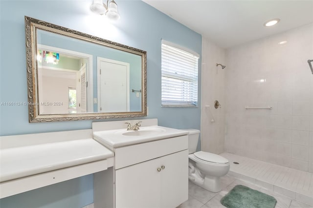 bathroom with a tile shower, vanity, toilet, and a healthy amount of sunlight