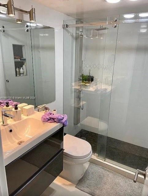 bathroom with vanity, a shower with shower door, and toilet