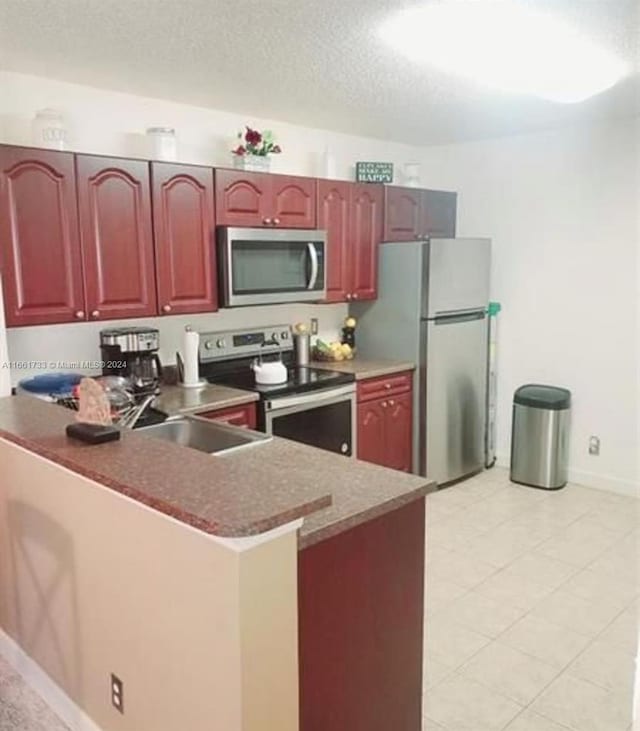 kitchen featuring kitchen peninsula, a textured ceiling, appliances with stainless steel finishes, and sink