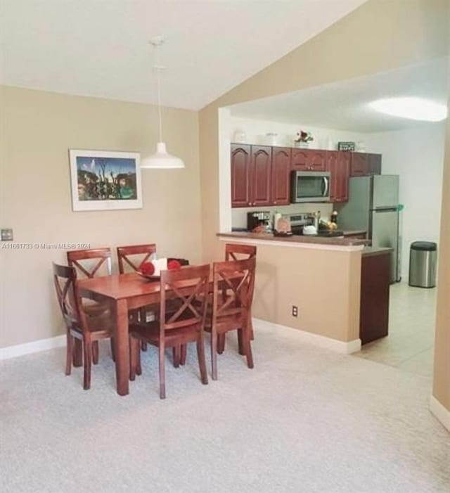 carpeted dining room featuring vaulted ceiling