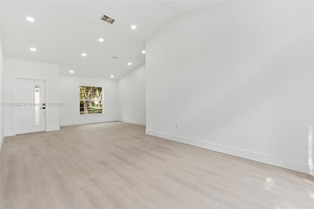 spare room featuring light hardwood / wood-style flooring and lofted ceiling