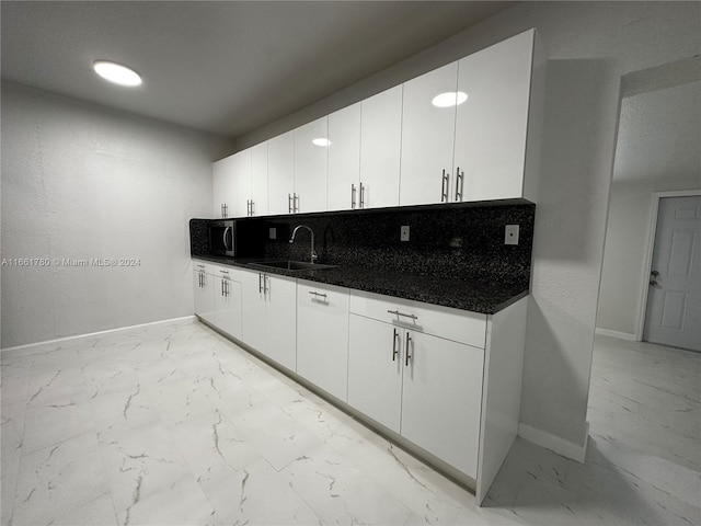 kitchen featuring sink, decorative backsplash, and white cabinetry