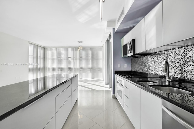 kitchen with white cabinets, appliances with stainless steel finishes, dark stone counters, and sink