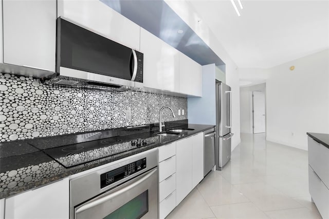 kitchen with decorative backsplash, white cabinetry, dark stone countertops, and stainless steel appliances