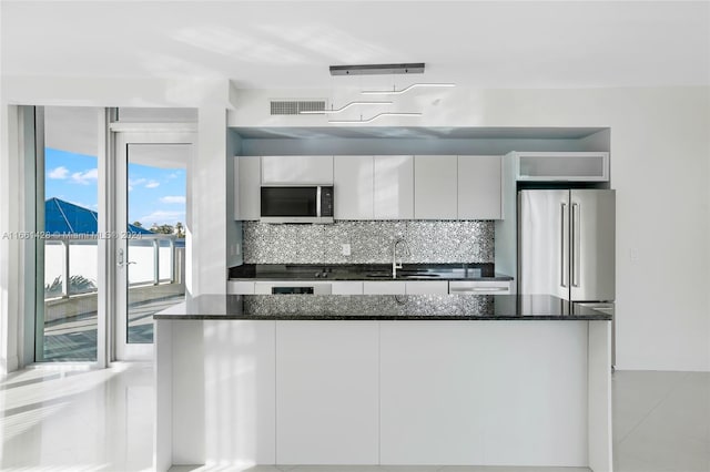 kitchen featuring backsplash, sink, dark stone countertops, appliances with stainless steel finishes, and white cabinetry