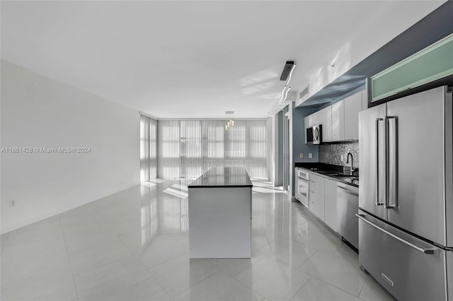 kitchen with backsplash, sink, a kitchen island, white cabinetry, and stainless steel appliances