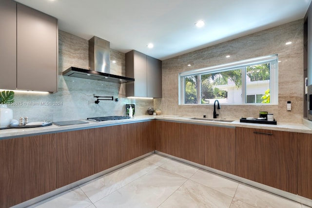 kitchen featuring backsplash, sink, wall chimney exhaust hood, and stainless steel gas cooktop