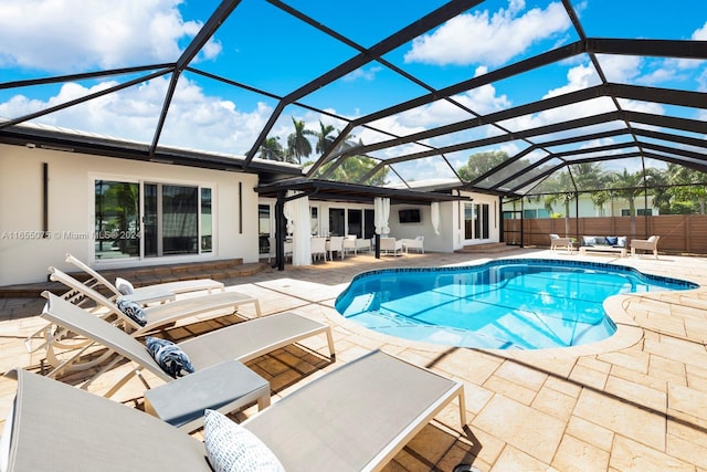 view of pool featuring glass enclosure, outdoor lounge area, and a patio