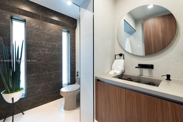 bathroom featuring tile patterned floors, vanity, tile walls, and toilet