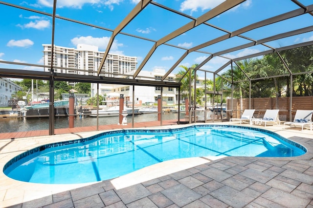 view of swimming pool featuring glass enclosure, a patio area, and a water view