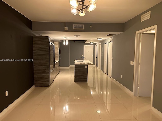 hallway with a notable chandelier and light tile patterned floors