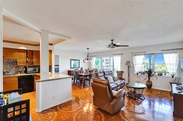 tiled living room with a textured ceiling, ceiling fan with notable chandelier, sink, and ornamental molding