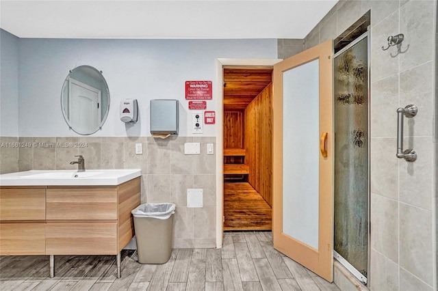 bathroom with vanity, tile walls, hardwood / wood-style floors, and a shower with door