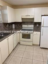 kitchen with decorative backsplash, white appliances, white cabinetry, and light tile patterned floors