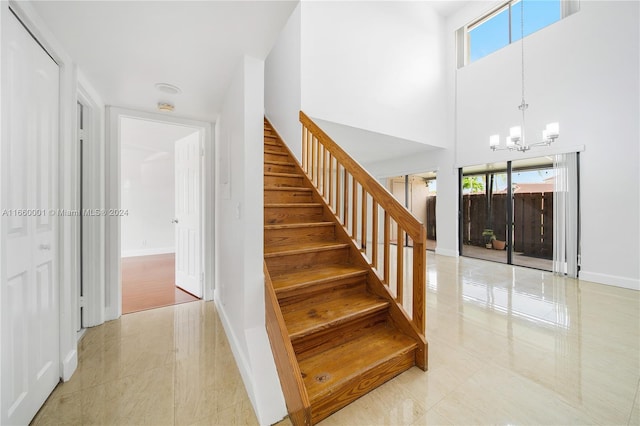 stairway featuring a chandelier, a high ceiling, and tile patterned flooring