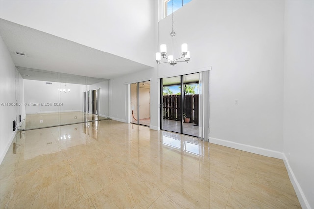 spare room featuring a high ceiling, a chandelier, and plenty of natural light