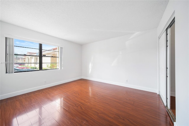 spare room with a textured ceiling and dark hardwood / wood-style floors