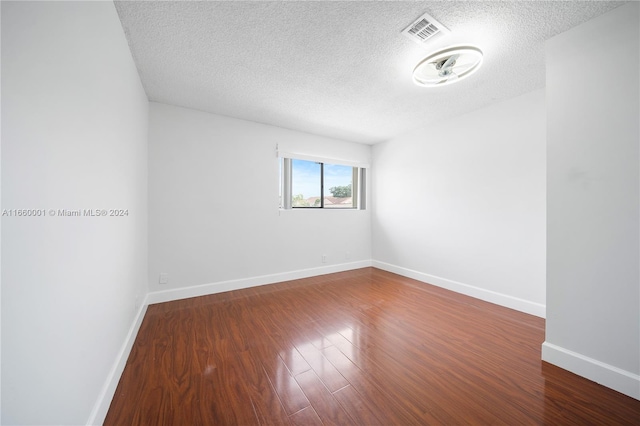 spare room featuring a textured ceiling and hardwood / wood-style floors