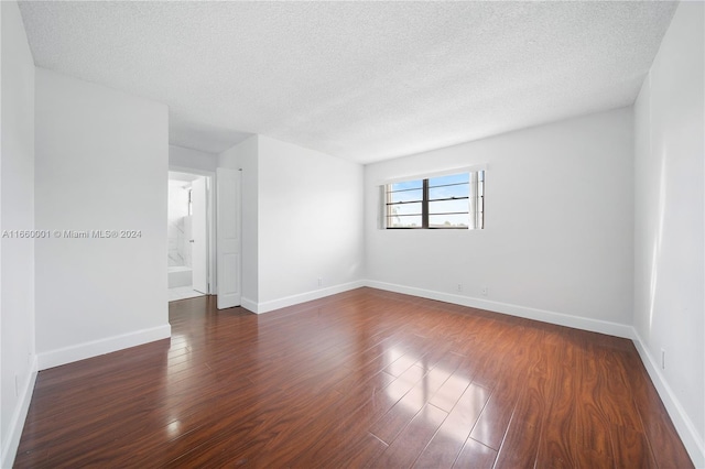 unfurnished room with a textured ceiling and dark hardwood / wood-style flooring