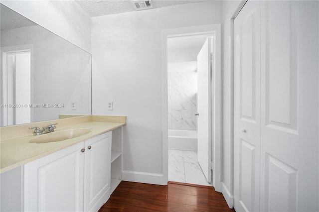 bathroom with vanity, a shower, hardwood / wood-style floors, and a textured ceiling