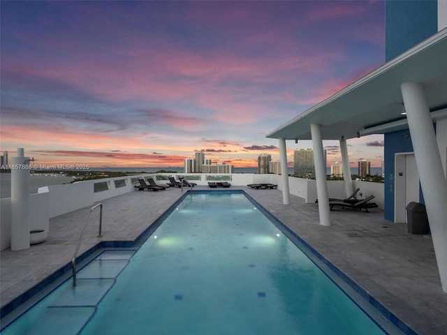 pool at dusk with a patio area