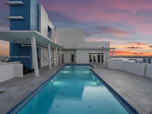 pool at dusk with a patio area