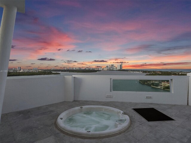 patio terrace at dusk featuring an outdoor hot tub