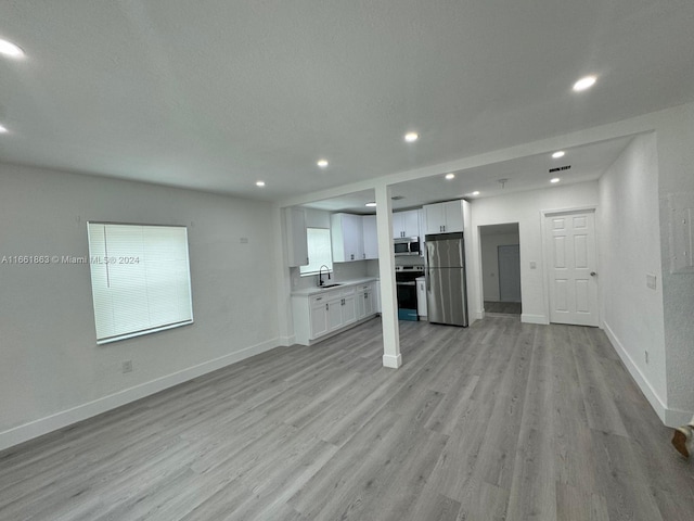 unfurnished living room with light hardwood / wood-style floors and sink