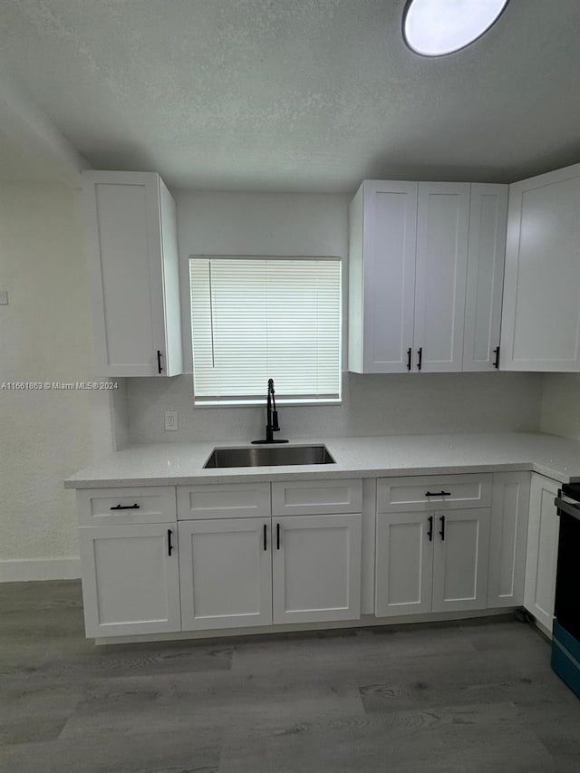 kitchen featuring a textured ceiling, sink, light hardwood / wood-style flooring, and white cabinets