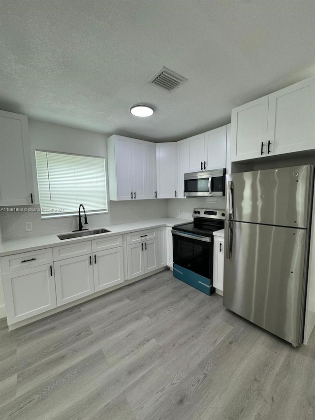 kitchen with light hardwood / wood-style flooring, stainless steel appliances, and white cabinetry