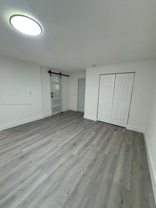 unfurnished bedroom featuring light hardwood / wood-style floors, a closet, and a barn door